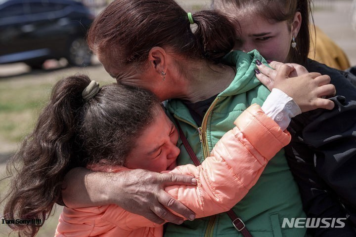 12일 우크라이나 하르키우주 보우찬스크 마을에서 피란길에 오른 11세 소녀 크리스티나(왼쪽)가 엄마를 부둥켜안고 울고 있다. 뉴시스
